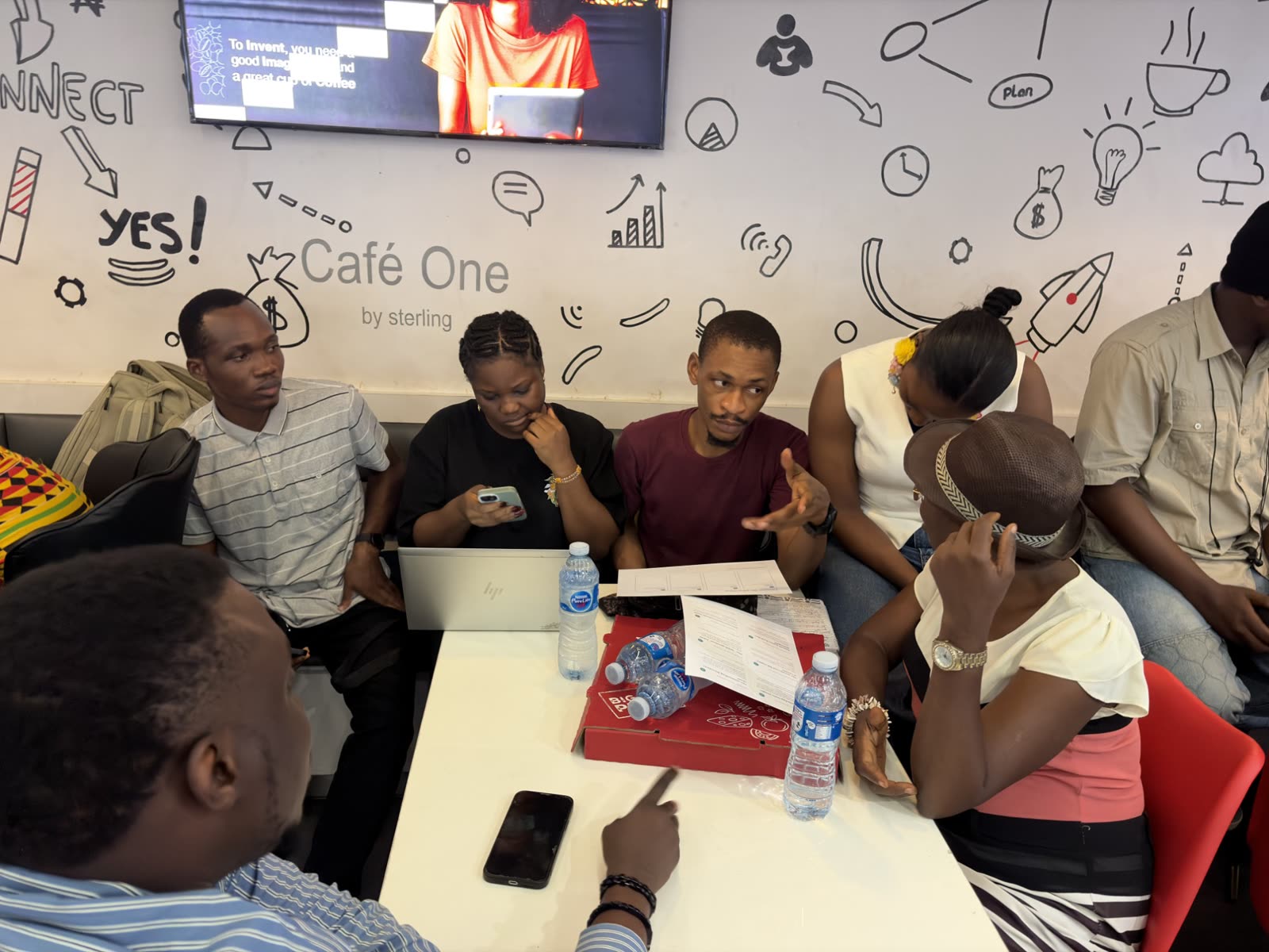 A team gathered around the printed workshop cards and a phone, talking through a process