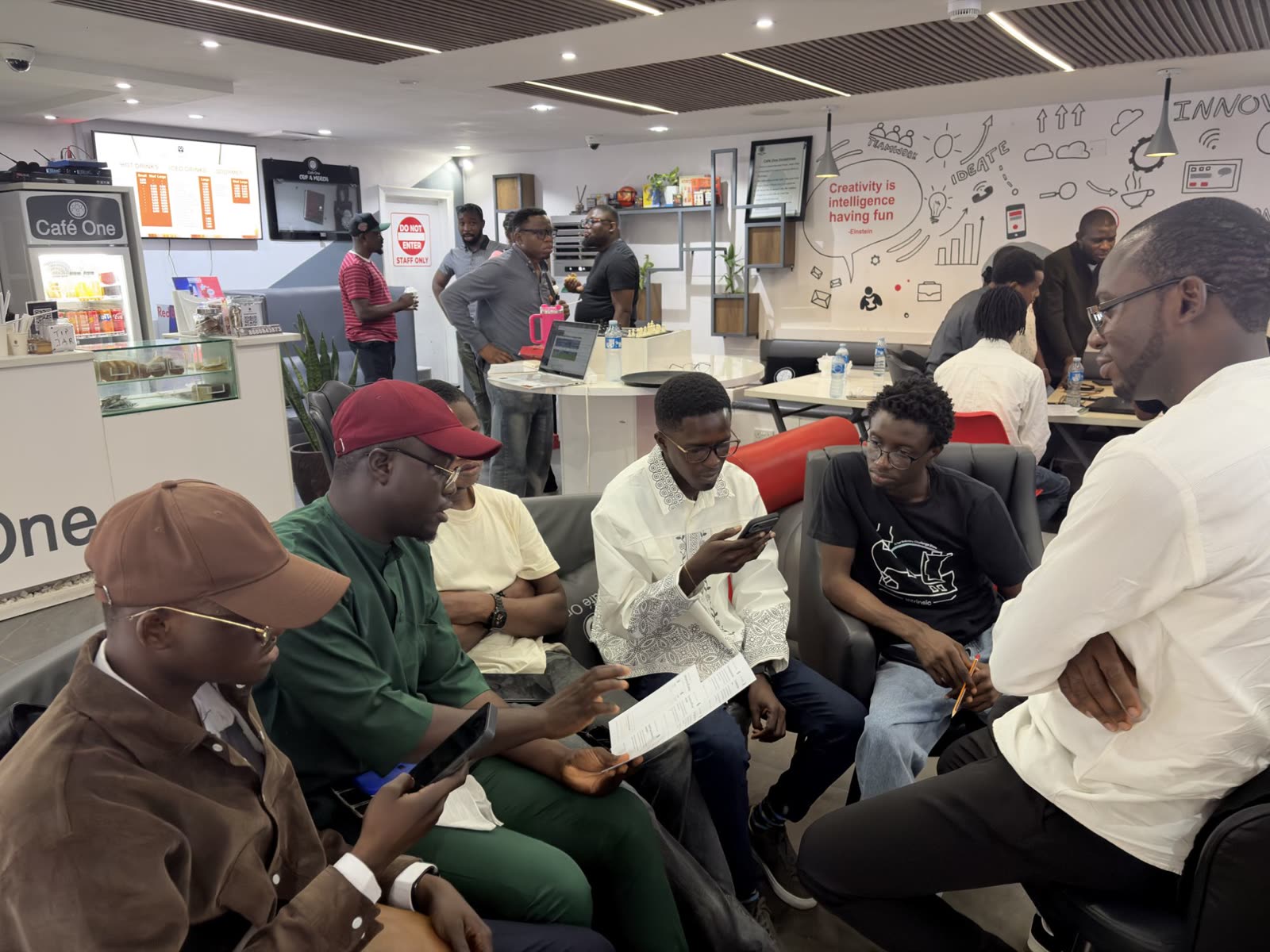 A group in a lounge reading a case card together while the rest of the room works in teams